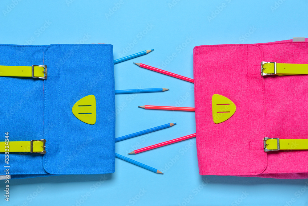 School backpacks and pencils on color background