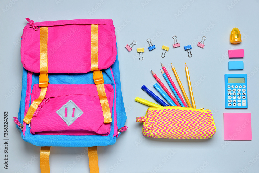 School backpack and stationery on light background