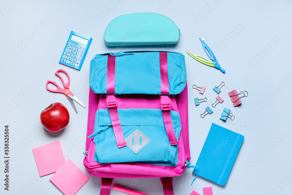 School backpack and stationery on light background