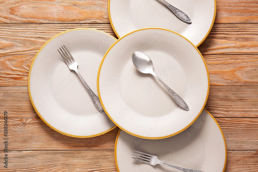 Clean plates and cutlery on wooden background