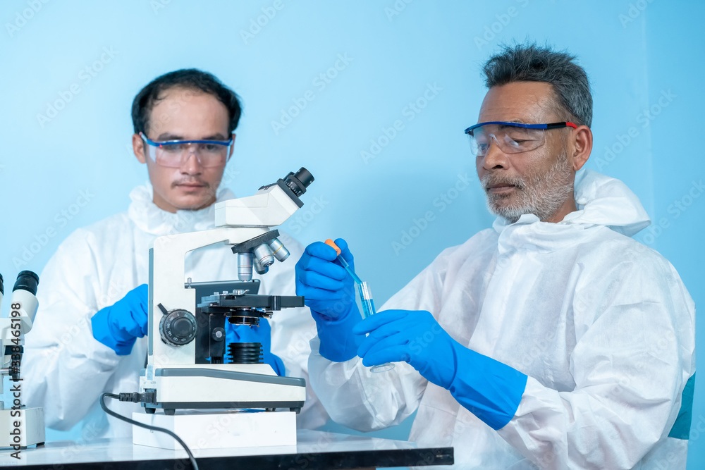 Close up of team Doctors in hazmat PPE protective clothing wear medical rubber gloves use microscope