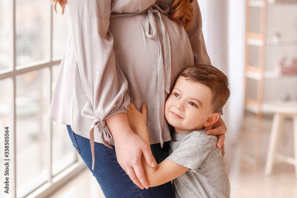 Beautiful pregnant woman with her little son at home