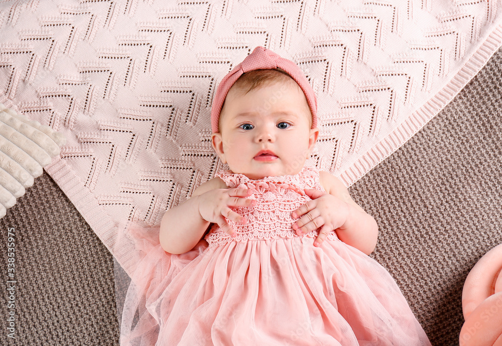 Cute baby in stylish clothes lying on bed