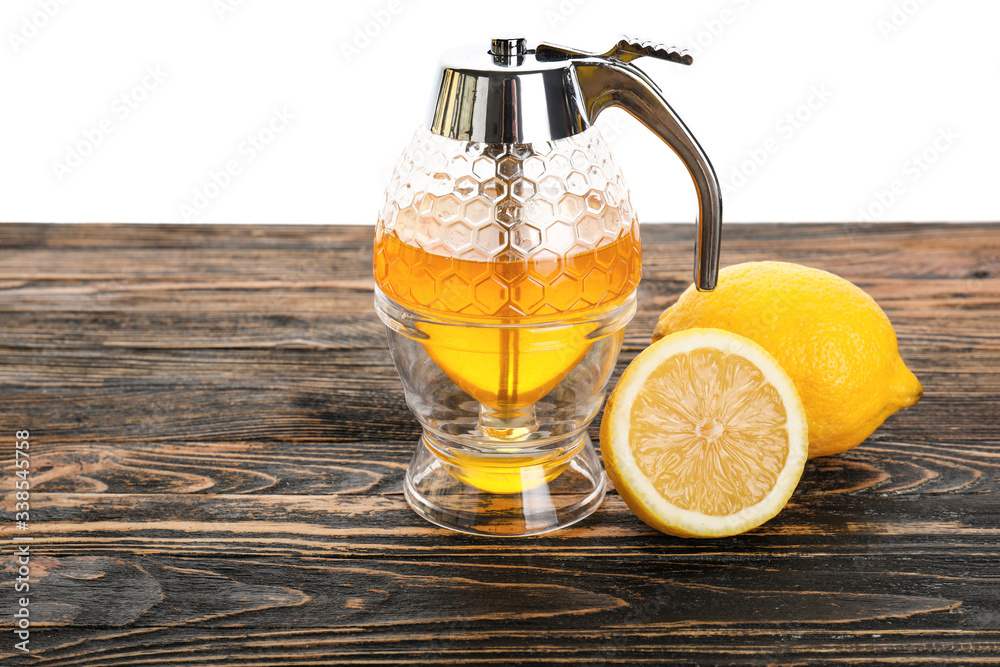 Honey-pot and lemon on table against white background