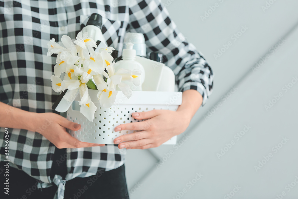 带着清洁用品和灰色背景春花的女人，特写