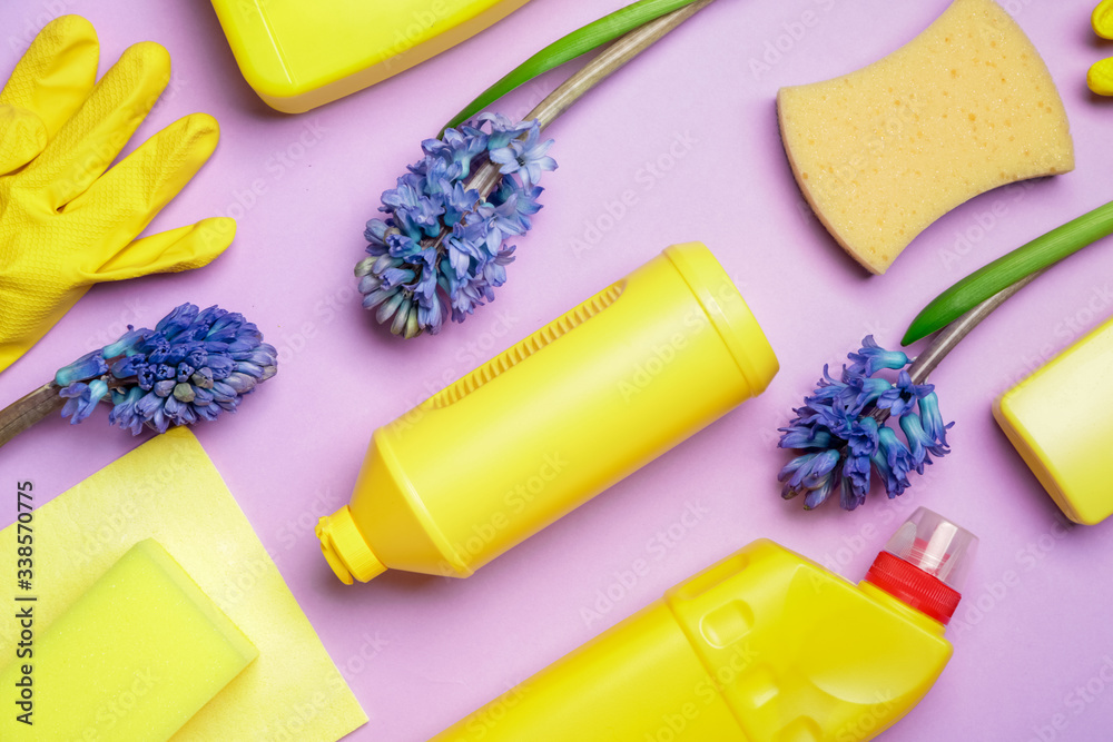 Set of cleaning supplies and spring flowers on color background