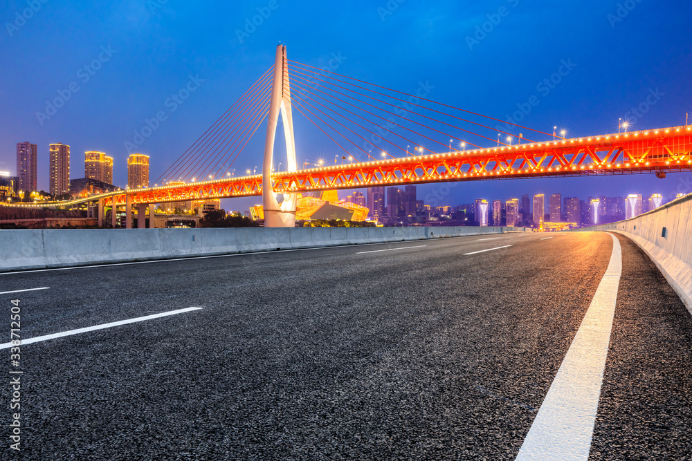 中国重庆，空旷的柏油路和城市天际线，夜晚有建筑。