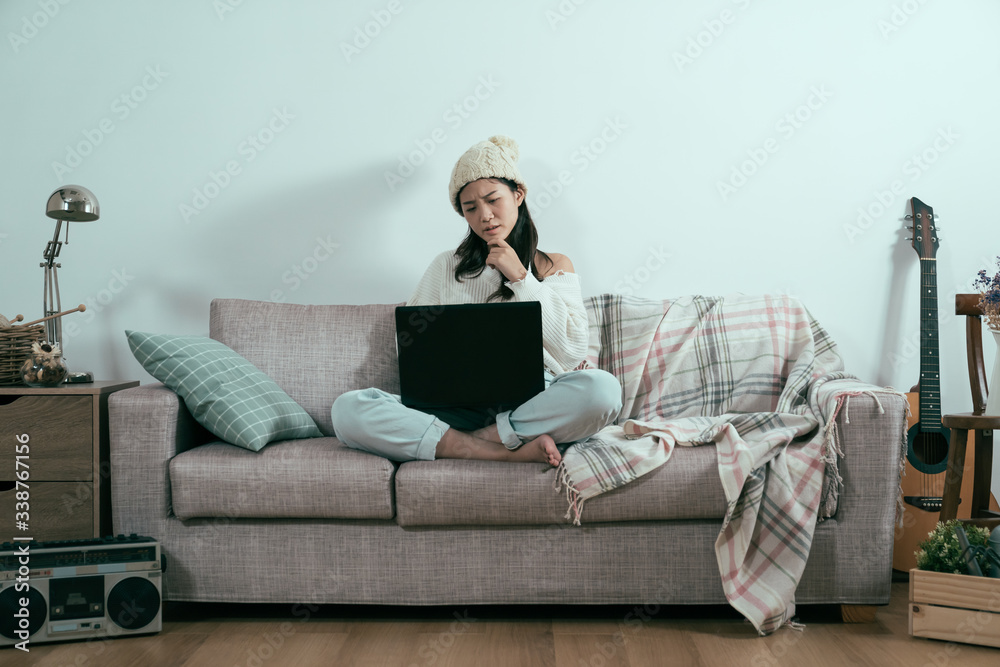 Serious young lady studying on cozy warm couch in living room at home. comfortable atmosphere with w