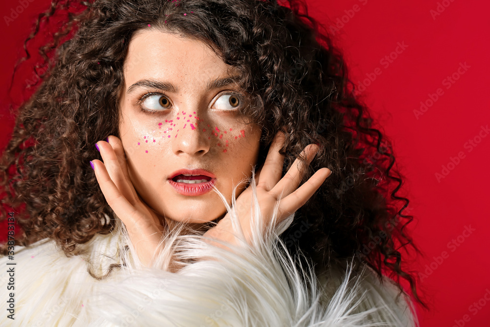 Surprised woman with beautiful curly hair and creative makeup on color background