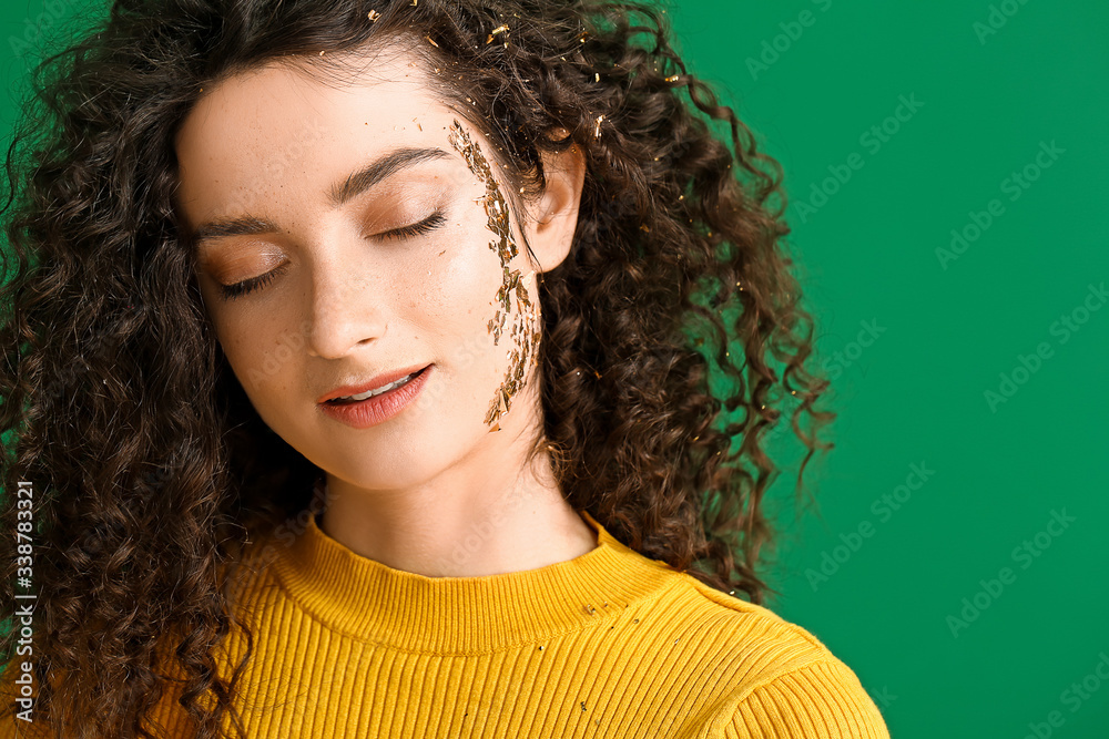 Young woman with beautiful curly hair and creative makeup on color background