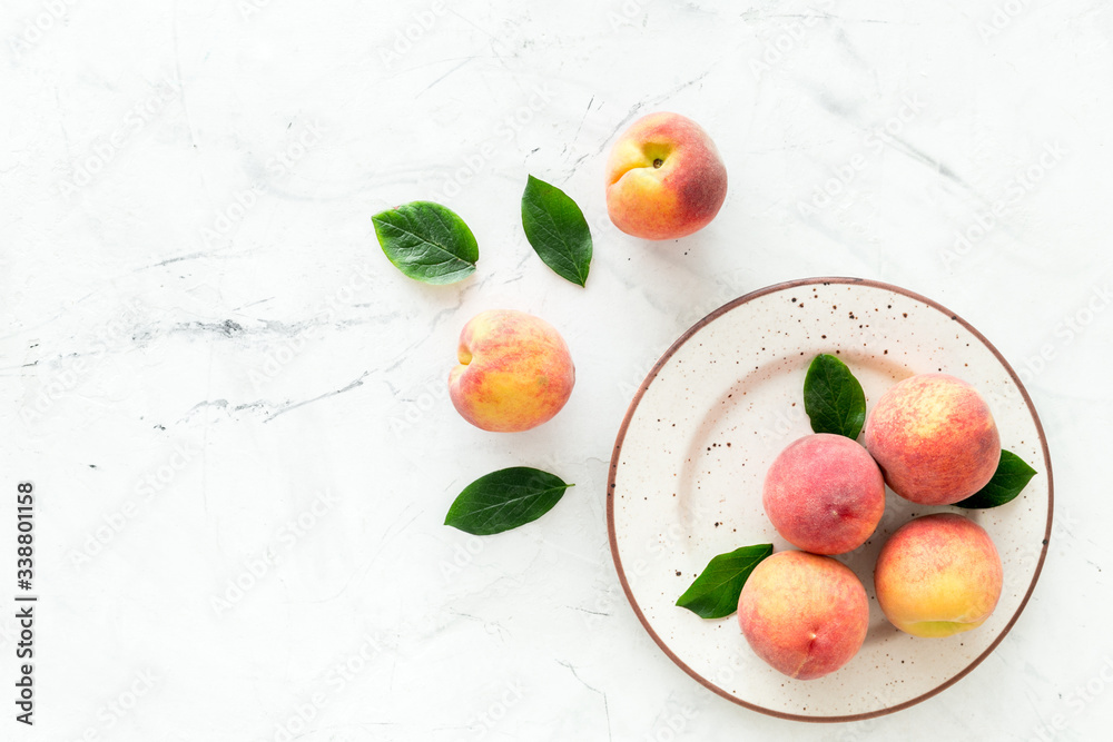 Summer fruits. Ripe red peaches on plate on white table top-down copy space