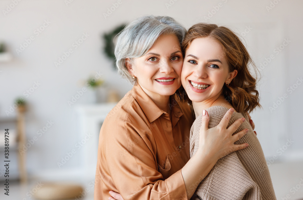 Happy senior woman with daughter hugging at home.