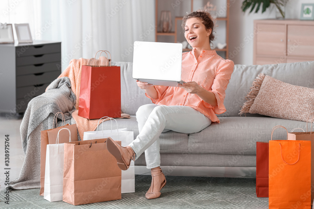 Beautiful young woman using laptop for online shopping at home