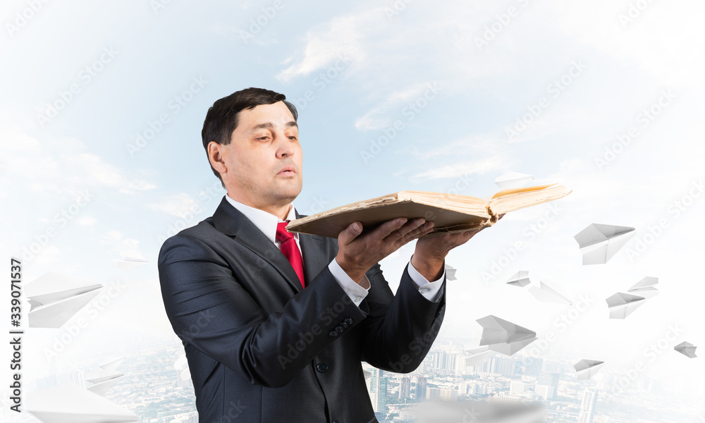 Serious businessman holding open old book