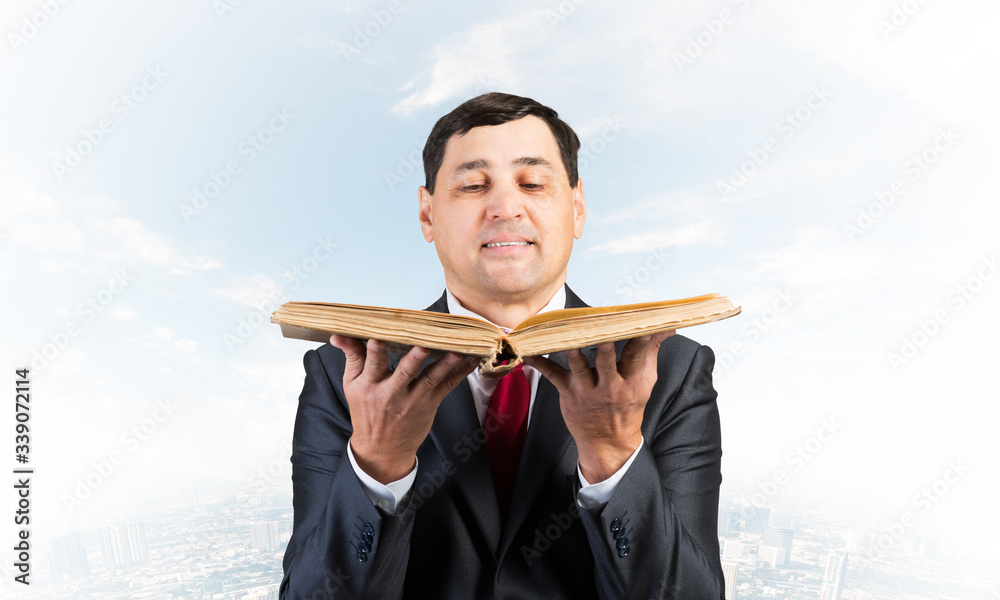 Happy businessman holding open old book