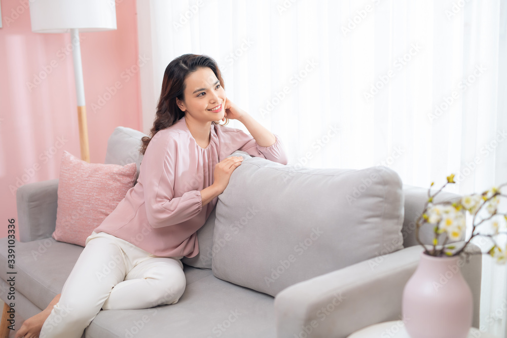 Beautiful young asian woman drinking coffee and relaxing on sofa.