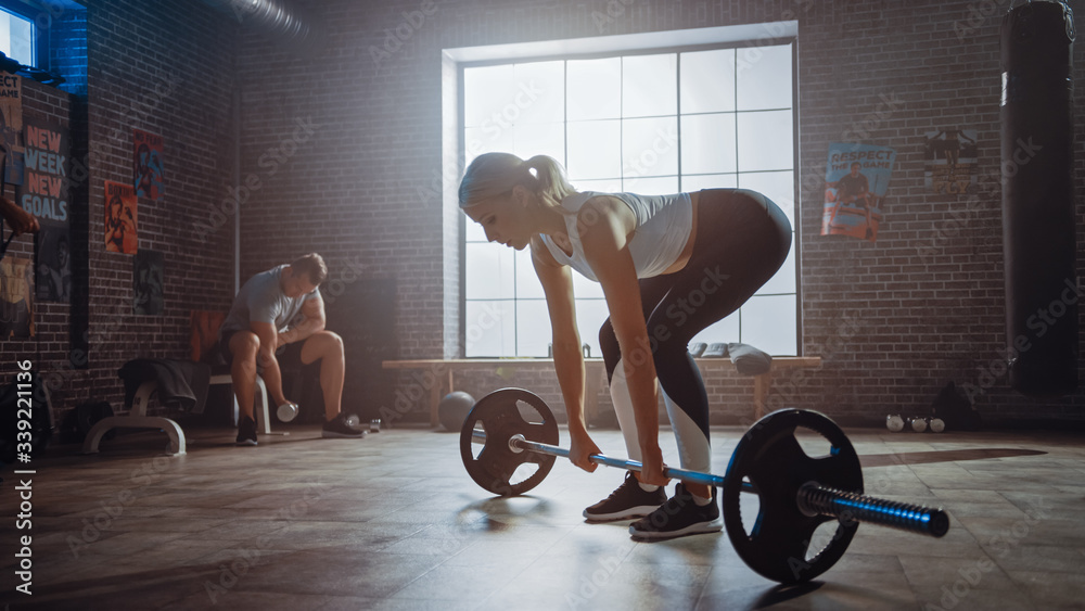 Beautiful Fit Athletic Blond Female is Lifting a Barbell from the Ground and Doing Back Strengthenin