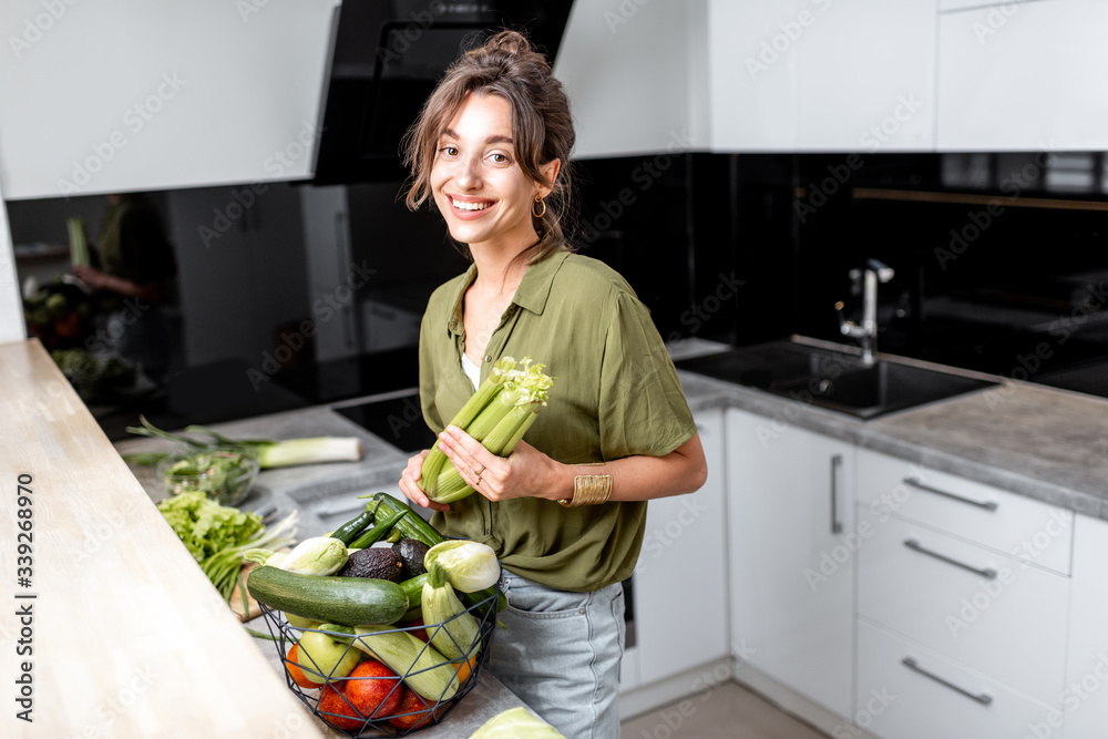 一个年轻快乐的女人的画像，家里的厨房里有健康的生食。素食主义，