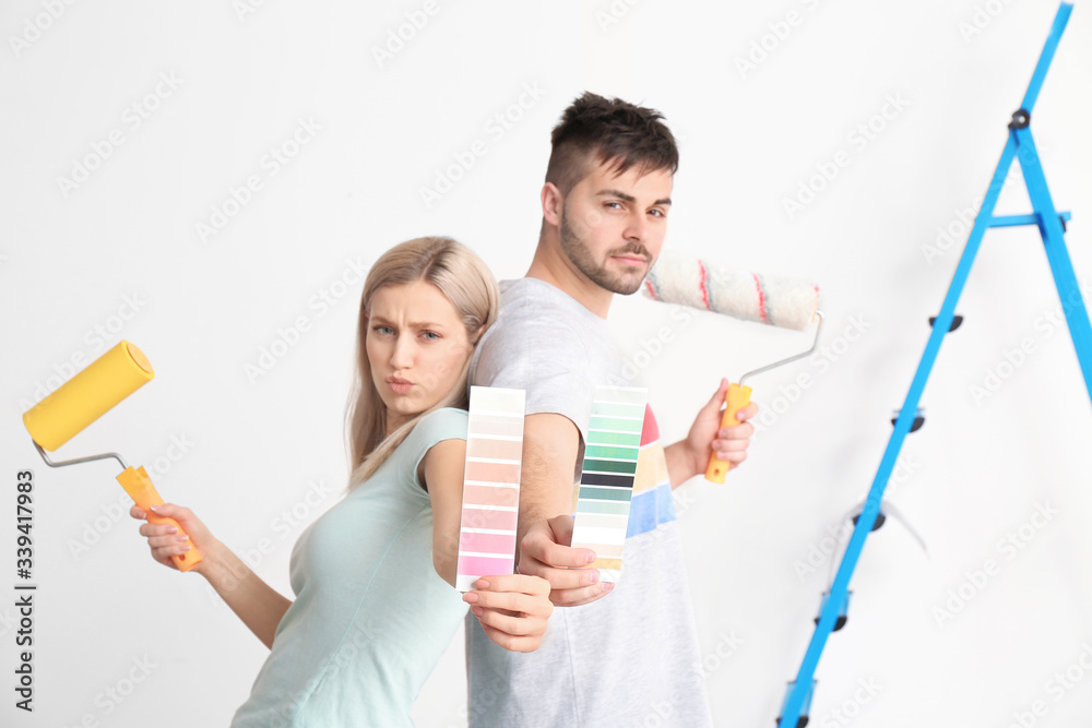 Young couple with color swatches and paint roller on white background