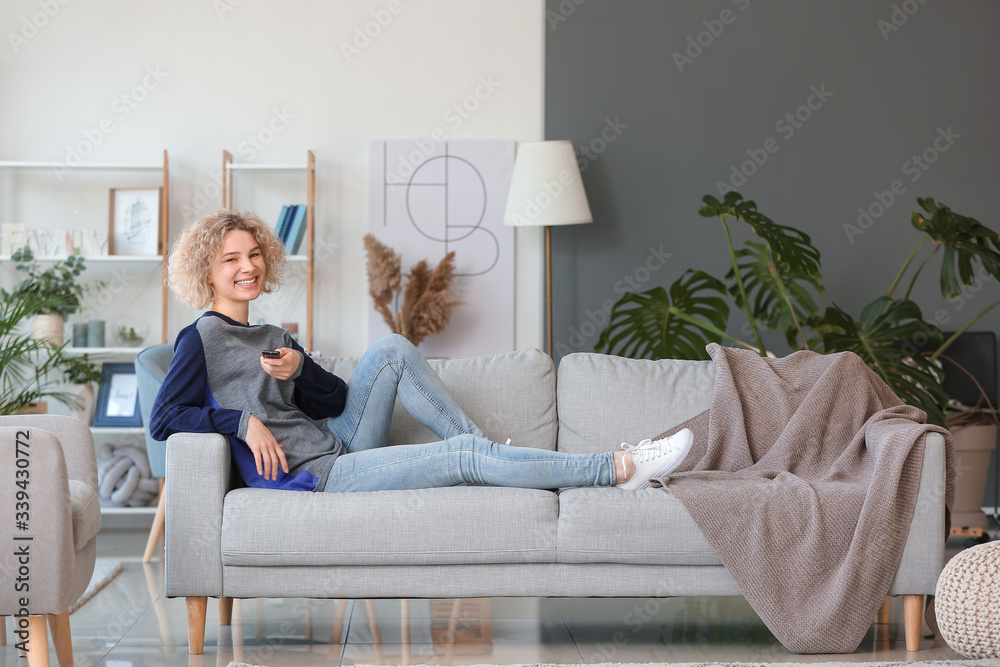 Beautiful young woman watching TV at home