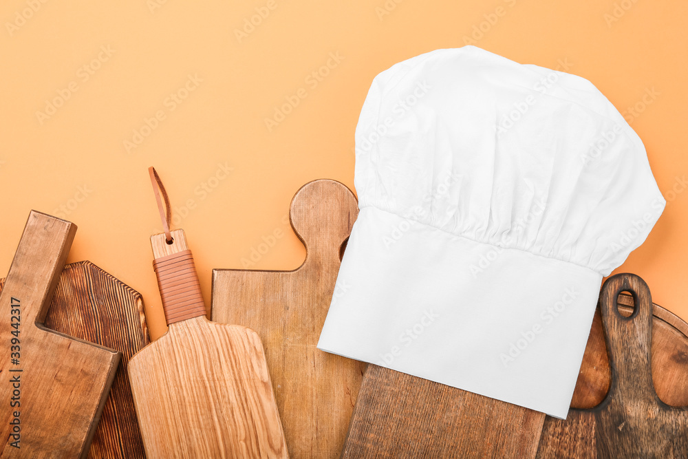 Composition with chefs hat and wooden boards on color background