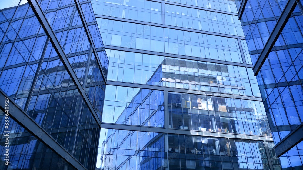 Blue curtain wall made of toned glass and steel constructions under blue sky. A fragment of a buildi