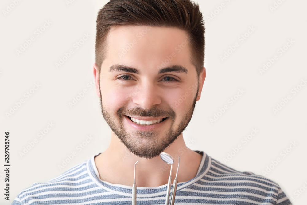 Happy smiling young man with dentists tools on white background