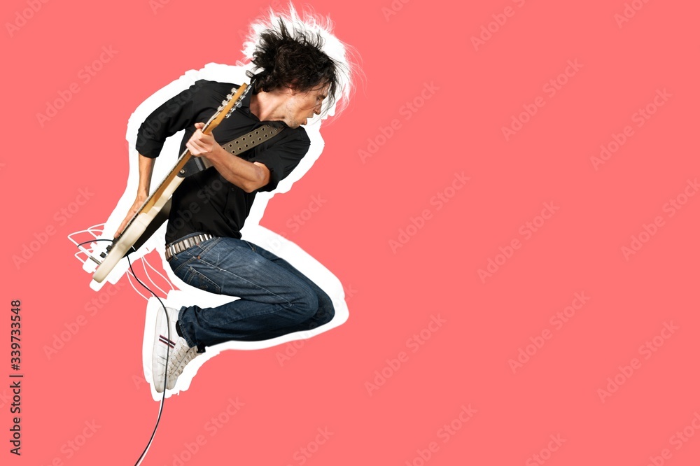 Male guitarist playing music on guitar and jump