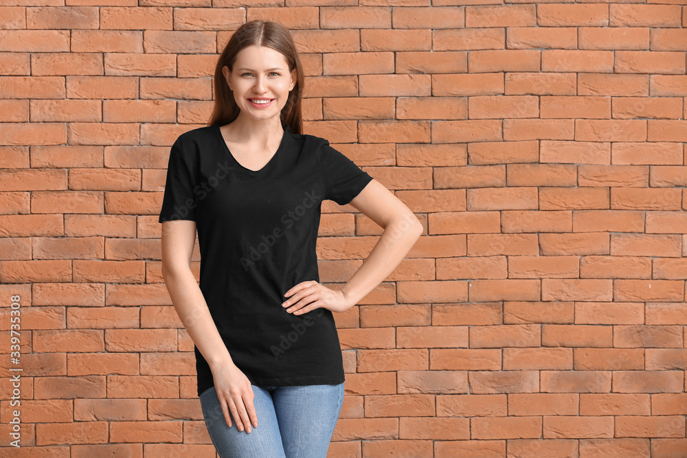 Young woman in stylish t-shirt on brick background