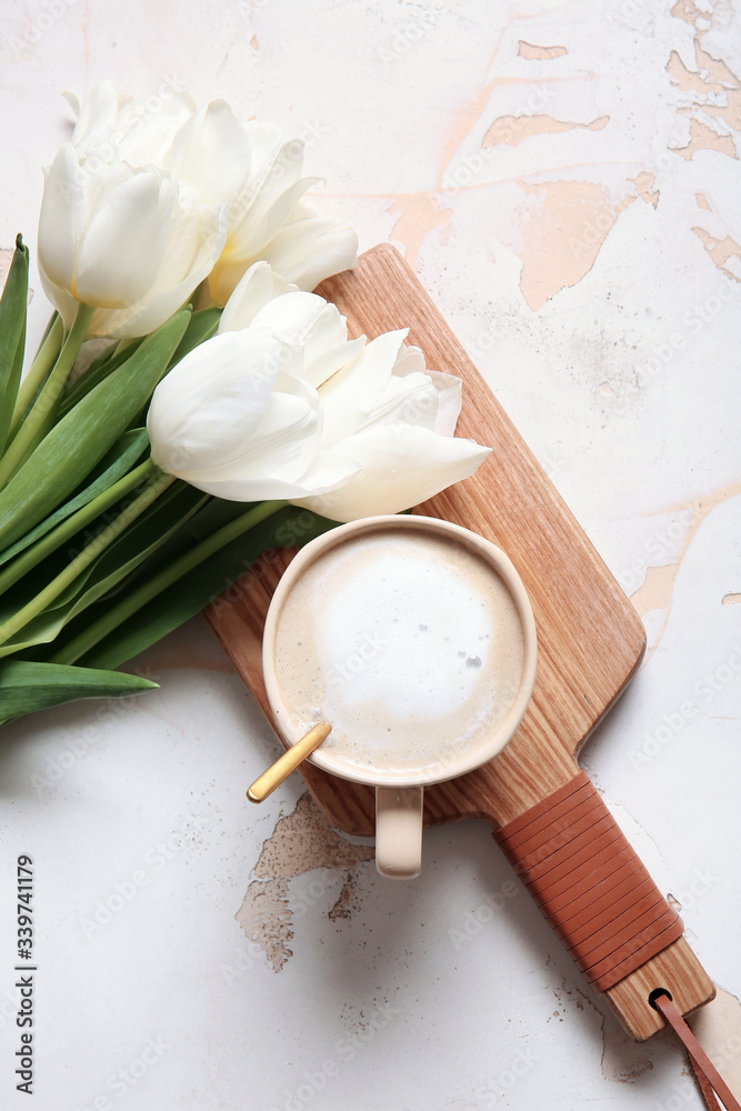 Cup of coffee and bouquet of flowers on light background