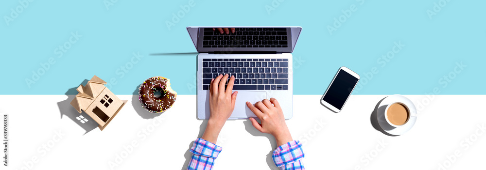 Woman using a laptop computer with a donut and a cup of coffee