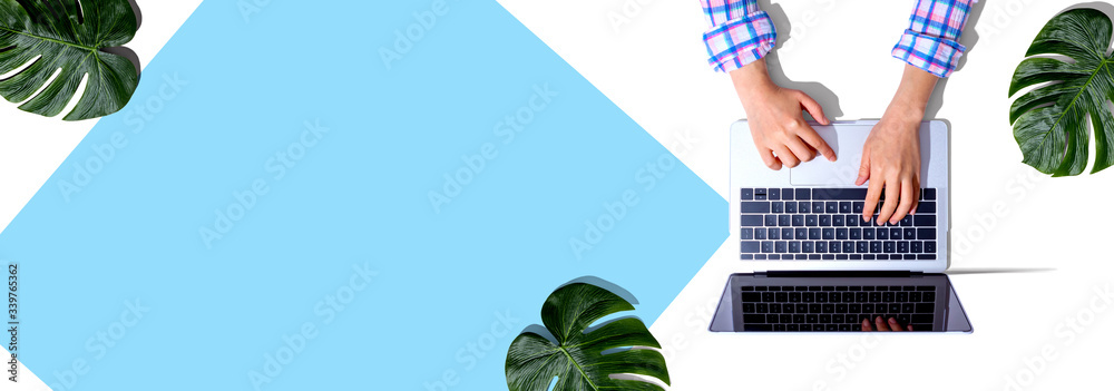 Person using a laptop computer with tropical leaves from above