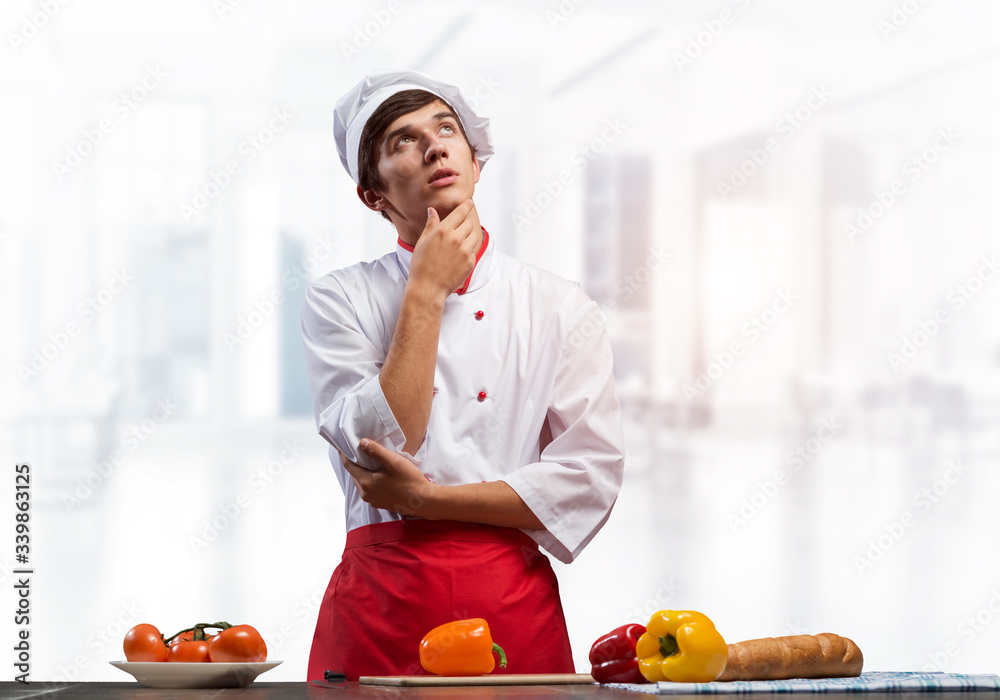 Young male chef standing with folded arms