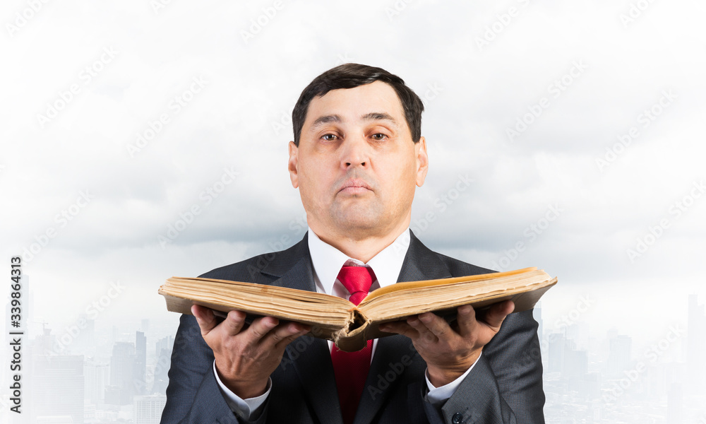 Serious businessman holding open old book