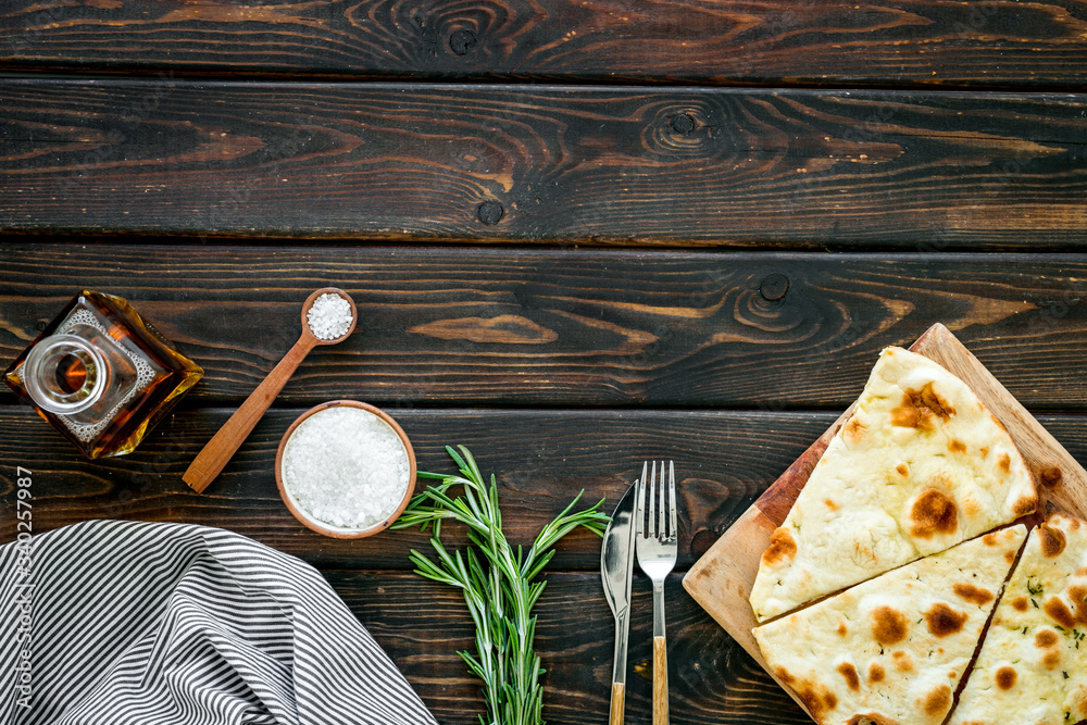 Italian focaccia with cheese and rosemary on dark wooden background top-down copy space