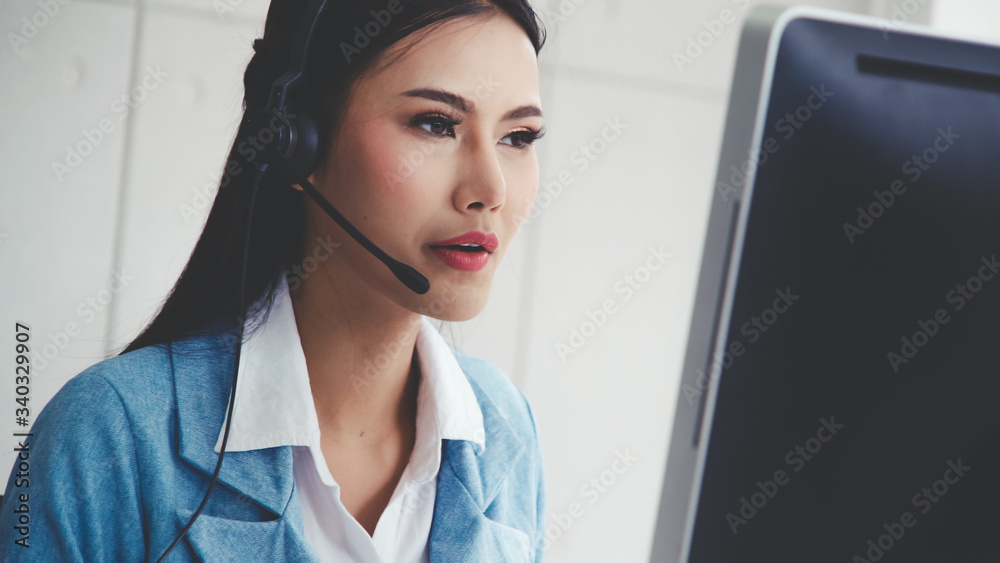 Customer support agent or call center with headset works on desktop computer while supporting the cu