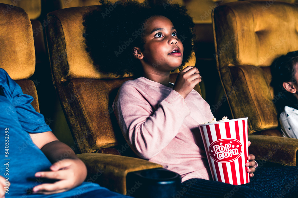 Three children having fun and enjoy watching movie in cinema