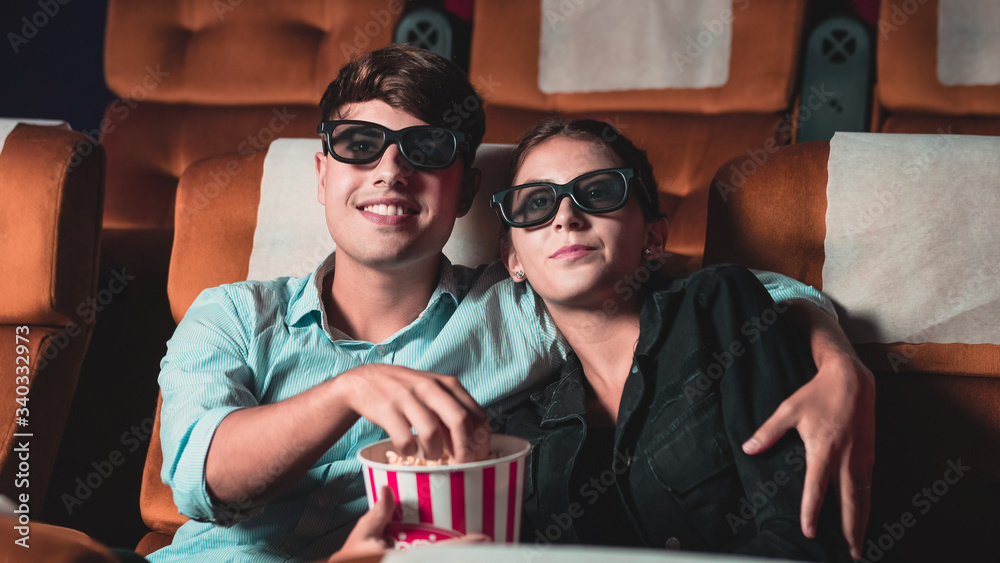 Man and woman in the cinema watching a movie with 3D glasses. with interest looking at the screen, e