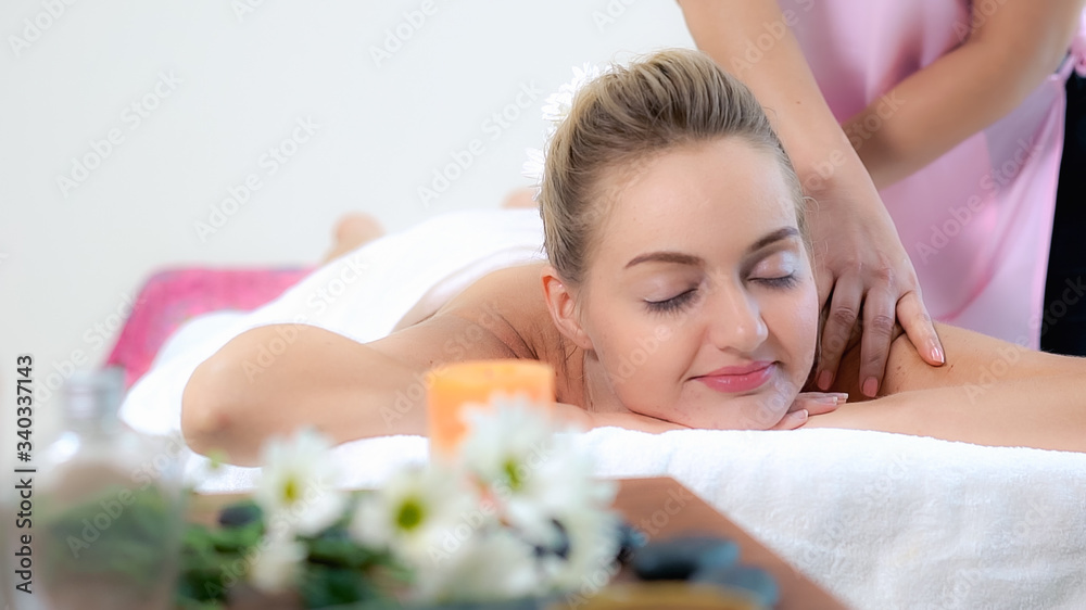 Relaxed woman getting back massage in luxury spa with professional massage therapist. Wellness, heal