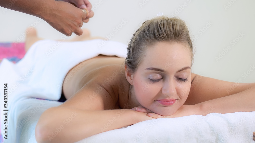 Relaxed woman getting back massage in luxury spa with professional massage therapist. Wellness, heal