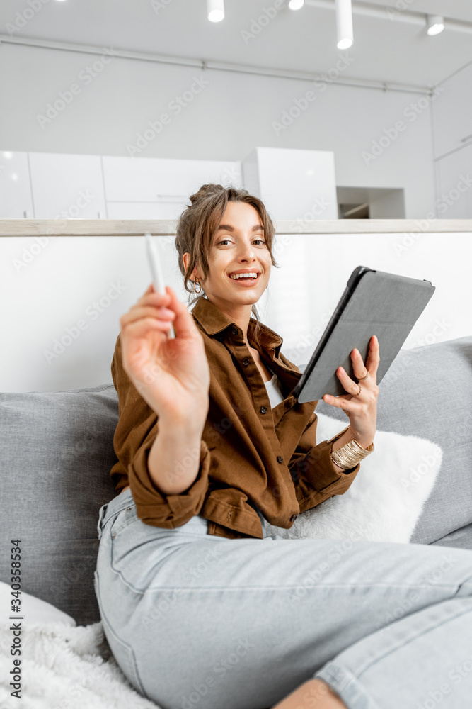 Portrait of a young relaxed woman working or surfing the internet on a digital tablet while sitting 