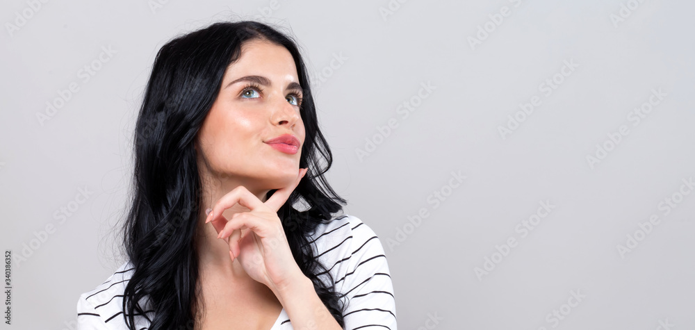 Young woman in a thoughtful pose on a gray background