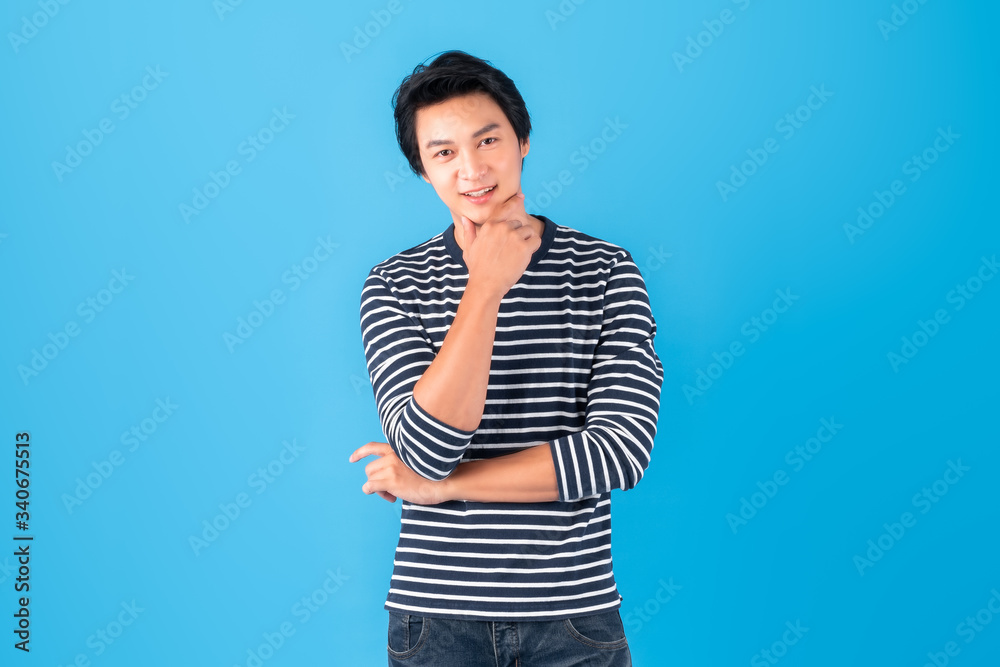 Handsome young Asian man smile hand touch chin over blue background