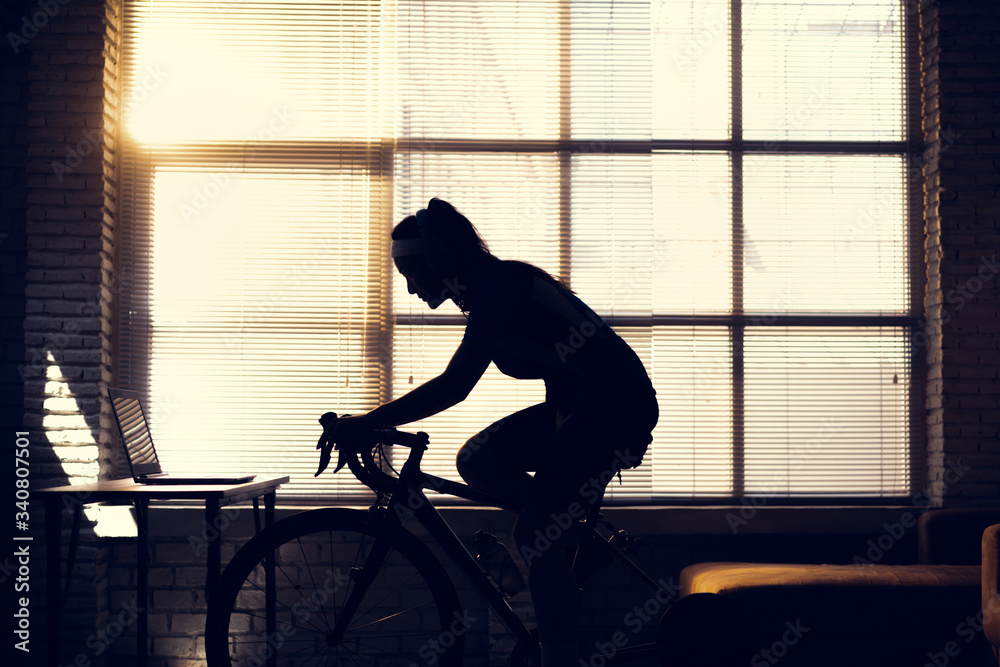 Asian woman cyclist. She is exercising in the house.By cycling on the trainer and play online bike g