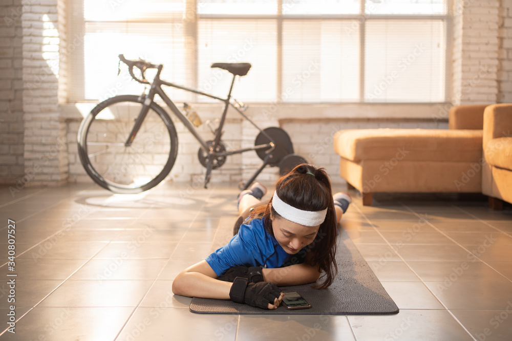 Asian woman relax from bike exercise in home. she plays phone