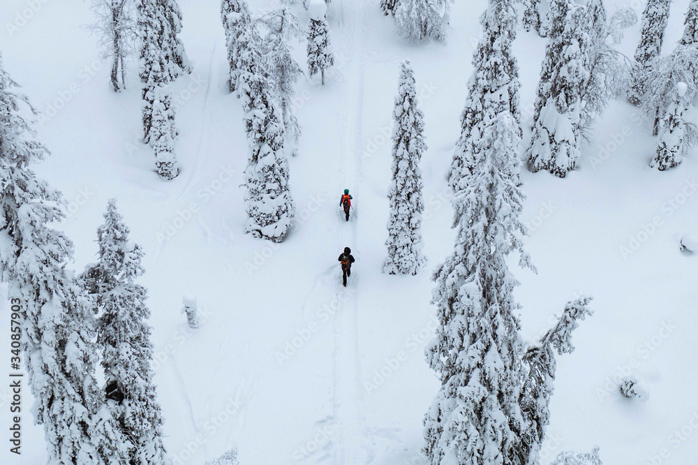 Drone shot of people trekking in a snowy forest in Lapland, Finland