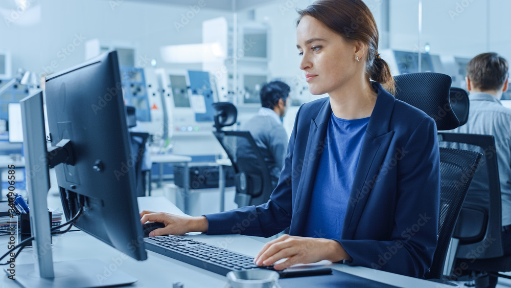 Modern Factory Office: Portrait of Young and Confident Female Industrial Engineer Working on Compute