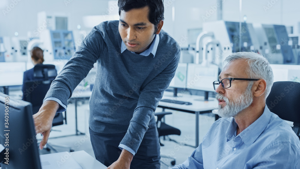 Modern Factory Office: Asian Project Manager Talks to Caucasian Senior Engineer whos Working on Com