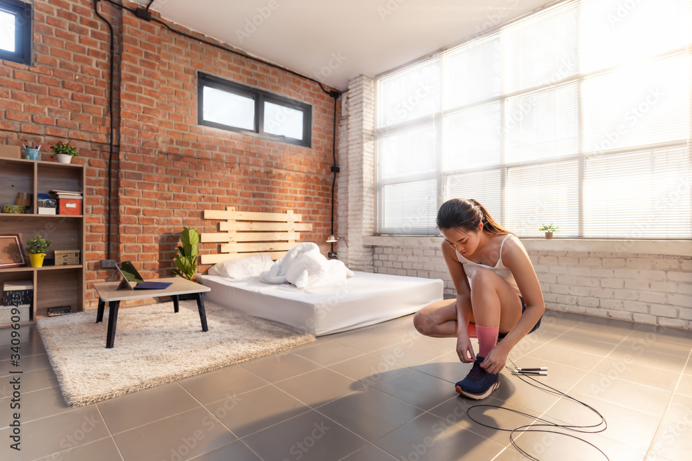 Asian women tie shoes before exercising at home.