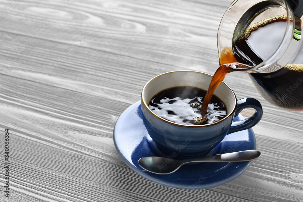 Pouring coffee with smoke on a cup on wooden background